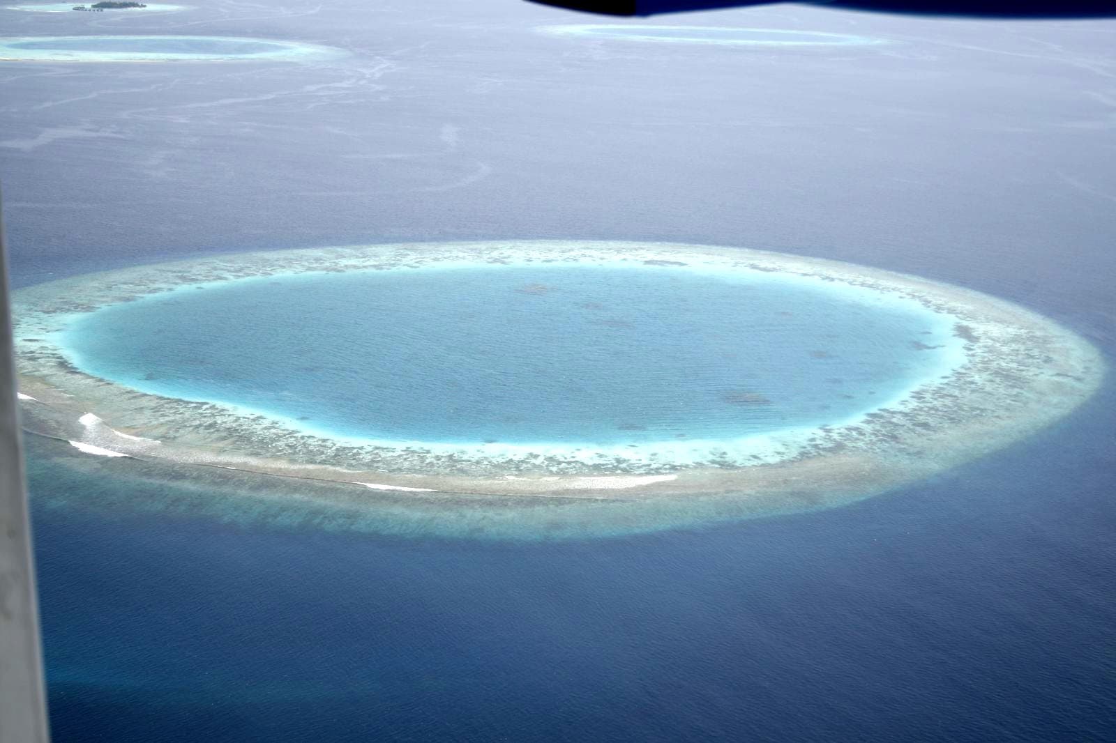Aerial view of a Maldivian resort island ringed by turquoise lagoon